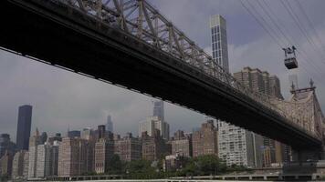 View of the Queensboro Bridge spanning over the East River, with the Roosevelt Island Tramway in action and the Manhattan skyline in the background video