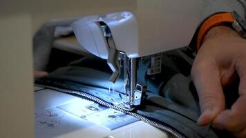 Person using a sewing machine with a garment, for repair work, customization, creation, upcycling, needle video