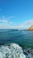 adraga playa y acantilados en soleado día. atlántico océano, Portugal. aéreo vista. Moviente hacia atrás a bajo nivel terminado rocas vertical video