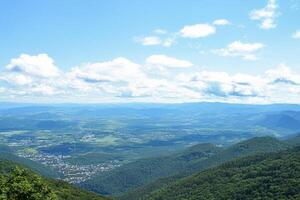 Mountaintop panoramic view valley, town, clouds photo