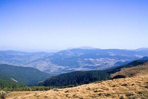Mountain vista, clear sky, grassy foreground, distant valley photo