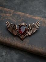 Red gemstone eagle wing brooch on brown leather background photo