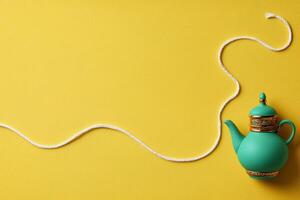 Teal teapot with gold accents on a yellow background with white string photo