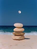 Zen stones stacked on a beach with a full moon in the background photo