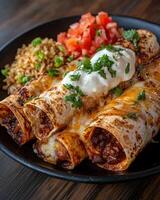 Close up of delicious beef enchiladas with cheese, sour cream, and cilantro, served with rice and pico de gallo photo