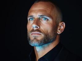 Close up portrait of a man with blue eyes and a beard, looking up thoughtfully photo