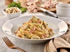 SPAGHETTI ALLA CARBONARA with mushroom and fork served in dish isolated on wooden table side view of italian fast food photo