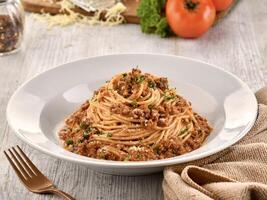 SPAGHETTI BOLOGNESE with fork served in dish isolated on wooden table side view of italian fast food photo