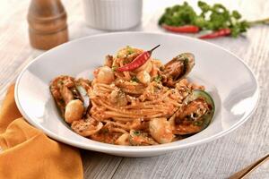 SEAFOOD DIABLO noodles with seashell and red chilli served in dish isolated on wooden table side view of italian fast food photo