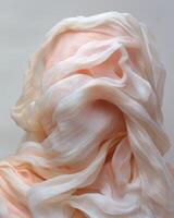 Peach colored silk fabric draped over a mannequin head photo