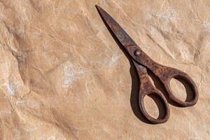 Rusty scissors on crumpled brown paper background photo