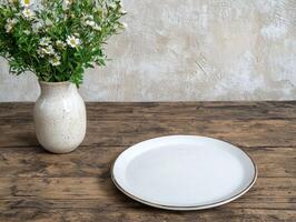Empty plate on rustic wooden table with flowers in vase photo