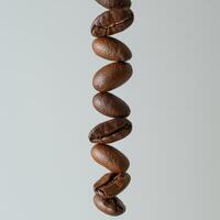 Close up of a vertical line of roasted coffee beans against a light gray background photo