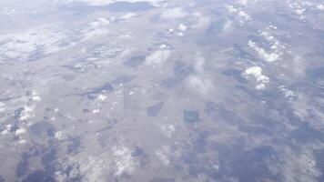 Aerial view of geometric farmland fields forming a patchwork landscape under soft clouds. Scenic rural countryside, peaceful horizon, tranquil atmosphere, and dynamic perspective. video