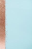 Rose gold glitter sparkles against a soft pastel blue background, creating a festive and elegant look. photo