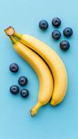 Fresh bananas and blueberries creatively arranged on a vibrant blue background. photo