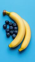 Fresh bananas and blueberries on a vibrant blue background. photo