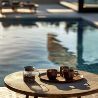 Warm sunlight illuminates a serene poolside coffee setup with copper mugs and a candle jar. photo