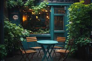 A small cozy cafe with a table outside, surrounded by green bushes photo