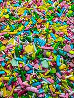 Multicolored small candies of different shapes. Top view. Bright vertical background photo