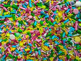 Multicolored small candies of different shapes. Top view. Bright horizontal background photo