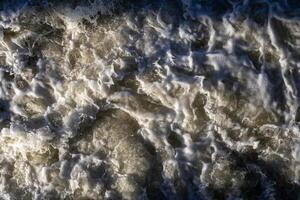 Rough flow of foaming water in the river, close-up, background. Rough flow photo