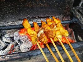 Satay goat satay, lamb, lamb or meat goat satay in grilling place with smoke by people with yummy looking. traditional satay from java, Indonesia. photo