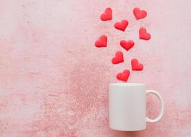 White mug mockup with heart shape confetti on pink background with copy space photo