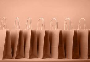Mocha Mousse - color of the year 2025. Row of brown shopping bags standing on the table photo