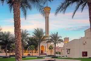 Islamic mosque with tall minaret framed by palm trees at sunset in peaceful courtyard photo