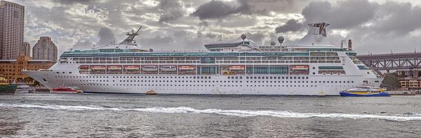 Large cruise ship docked at the harbor with dramatic cloudy sky and urban buildings in the background photo