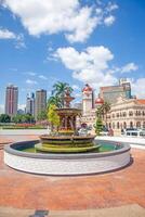 Historic clock tower and fountain in central Kuala Lumpur during daytime photo