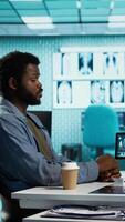 Vertical Medical interaction between a doctor and male patient with spinal pain, evaluating the radiography diagnostics, to provide feedback for young man. Effective health care advice. Camera B. video