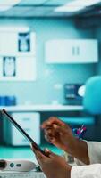 Vertical African american specialist reviewing data and records in her office, working on improving healthcare services at the treatment center. Healthcare provider works in a private clinic. Camera B. video