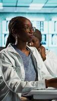 Vertical General practitioner uses a stethoscope to consult patient with illness, ensuring normal function of lungs and heartbeat. African american girl with a respiratory problem at checkup. Camera B. video