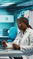 Vertical Professional medical consultation showcasing a female doctor and patient reviewing diagnostic results, fostering health care trust and accuracy for wellness. Black women at checkup. Camera B. video