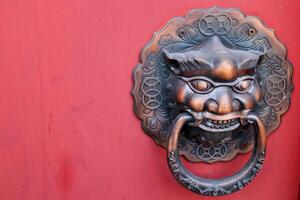 Ancient native head shape brass door knob on red painted wood plank in Thailand. photo