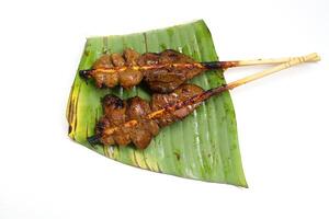 Top view chicken's livers in bamboo stick grilled on banana leaf and white background. photo