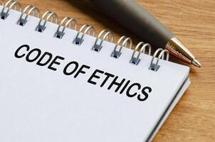 Code of ethics text on white notepad. Business code of ethics concept photo