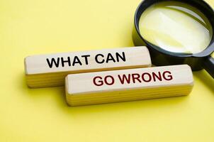 Side view of What Can Go Wrong text on wooden blocks with magnifying glass photo