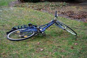 View of a blue broken bicycle lying on green grass photo