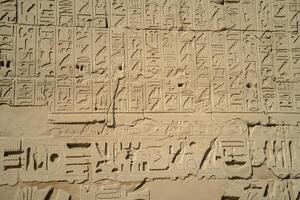 Egyptian ancient wall with hieroglyphs carved in the open air photo