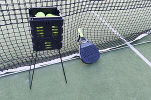 Paddle tennis racket, ball and net on the grass photo