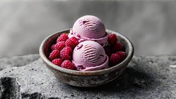 Delicious raspberry ice cream scoops surrounded by fresh raspberries in a textured bowl on a stone background photo