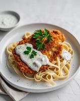 Crispy chicken schnitzel with creamy sauce and pasta garnished with parsleyCrispy chicken schnitzel with creamy sauce and pasta garnished with parsley. photo