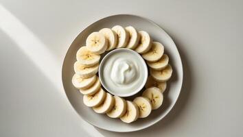 Banana Slices Arranged in a Circle on a White Plate with Yogurt photo