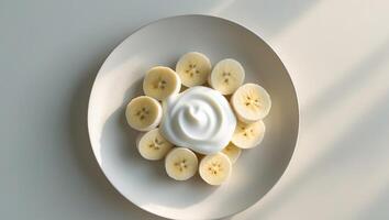 Banana Slices Arranged in a Circle on a White Plate with YogurtBanana Slices Arranged in a Circle on a White Plate with Yogurt. photo