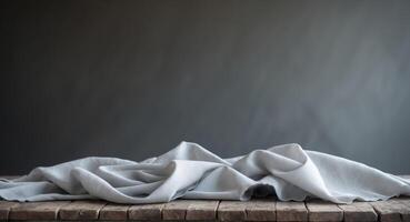 Gray Fabric Draped on Rustic Wooden Table with Dark BackgroundGray Fabric Draped on Rustic Wooden Table with Dark Background. photo