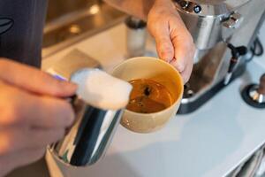 Adding whipped milk to espresso to make a latte photo