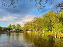 Trees reflection on the pond surface, spring park, lake, cloudy sky. photo